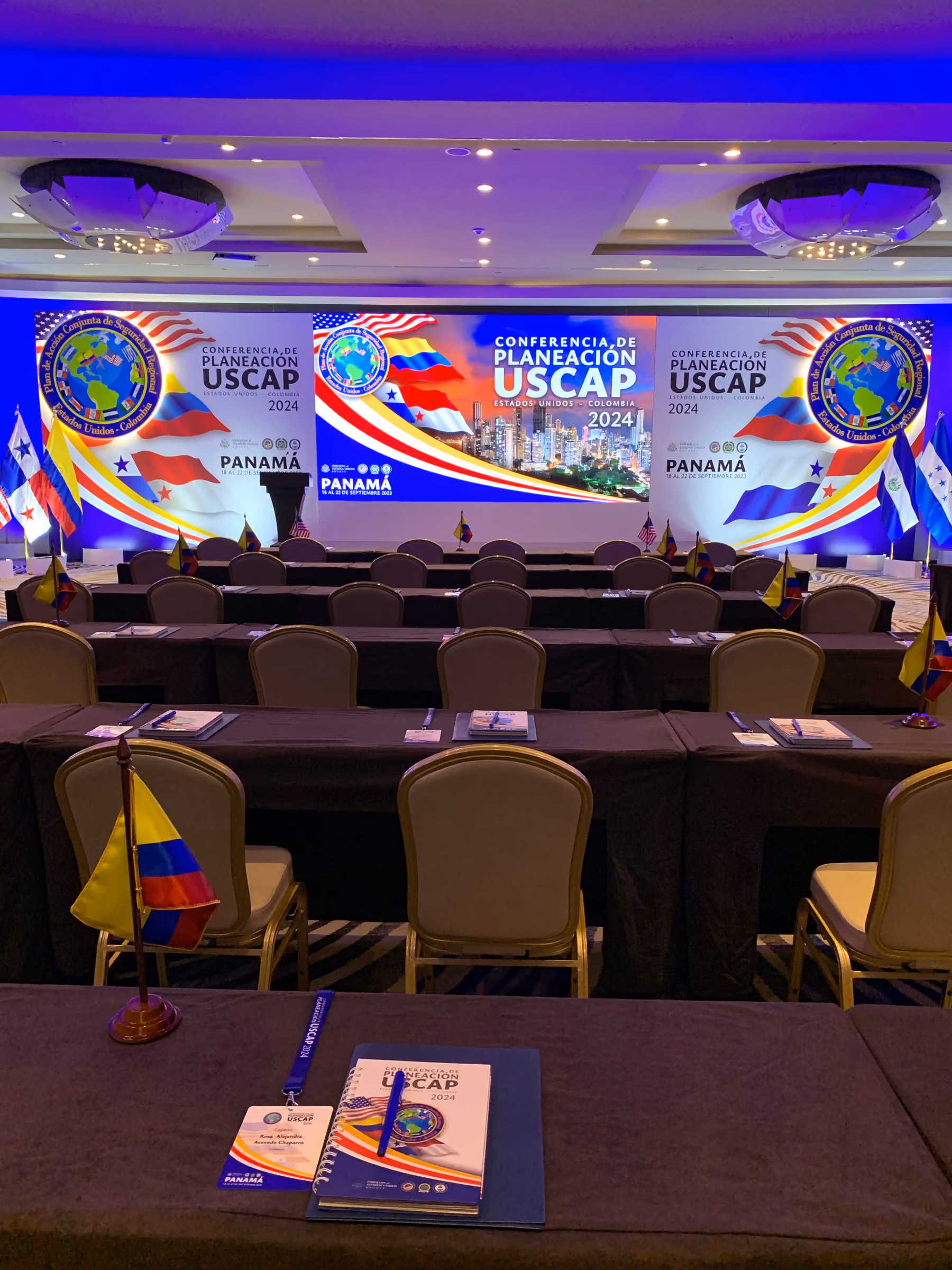 Salón de conferencia internacional con pantalla LED panorámica y mesas de delegaciones